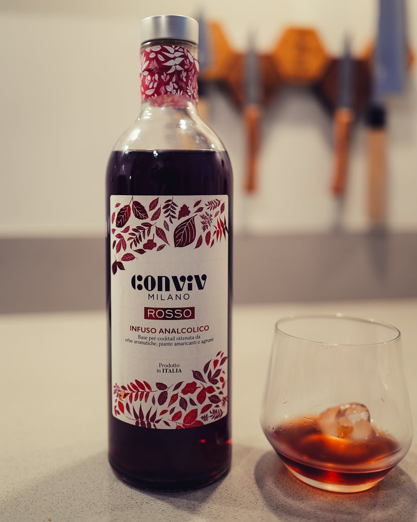 Conviv Milano Rosso bottle with a red leaf label beside a tumbler with ice and dark drink