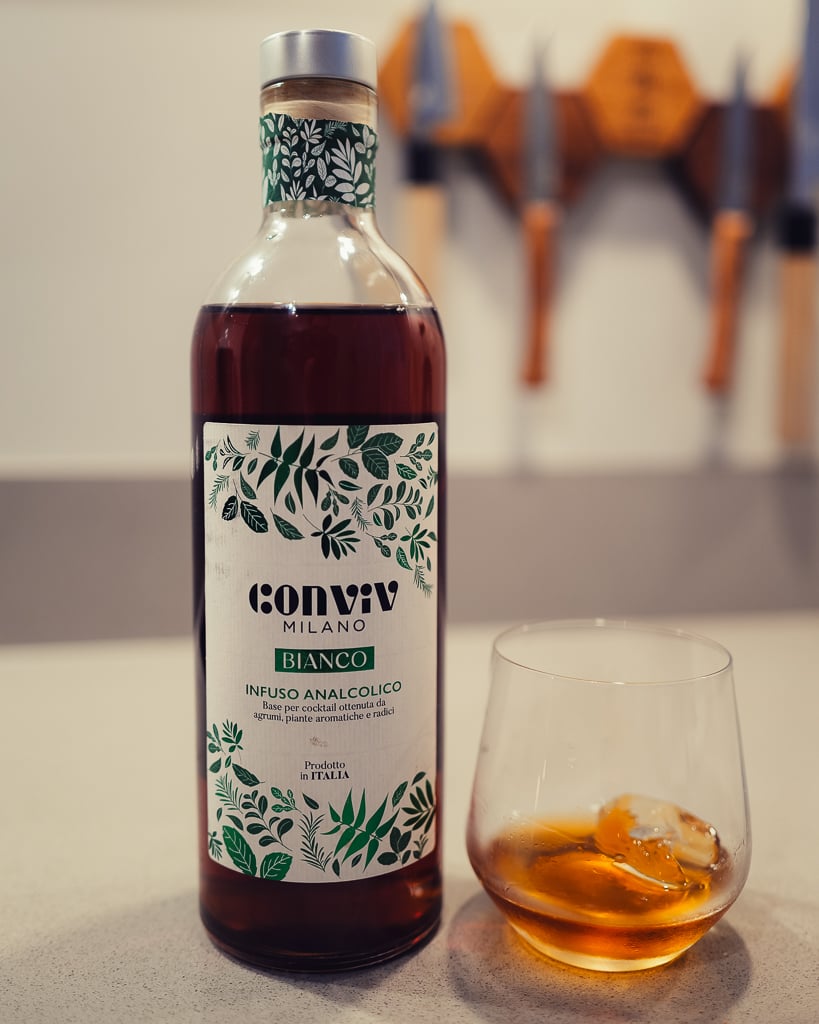 Conviv Milano Bianco bottle beside a tumbler of amber drink over ice