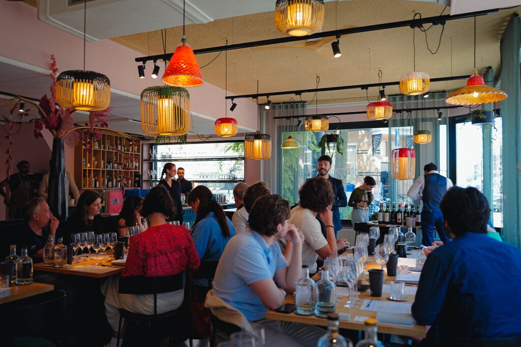 A busy tasting room with guests seated at tables under colourful hanging lamps