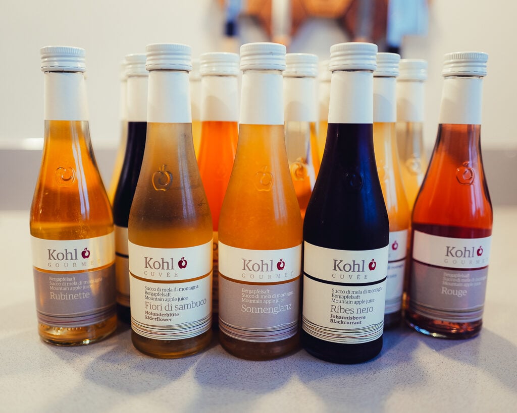 A row of Kohl mountain apple juice bottles in shades of amber, red and dark purple