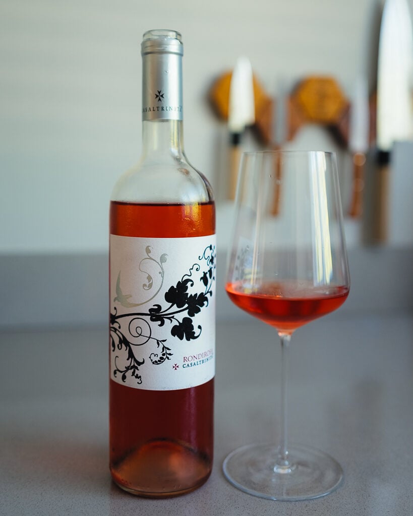 Casaltrinità Rondirosa rosé bottle with a floral label beside a glass of pink wine