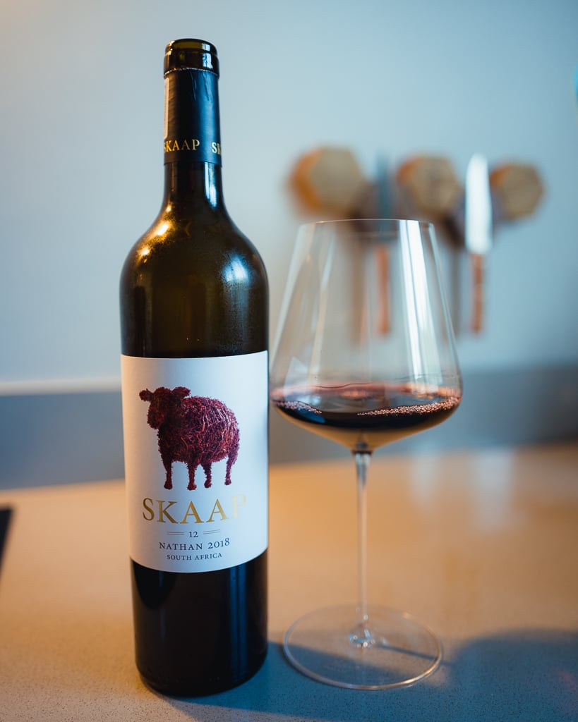 Skaap Nathan 2018 red wine bottle with a sheep label beside a glass of red wine