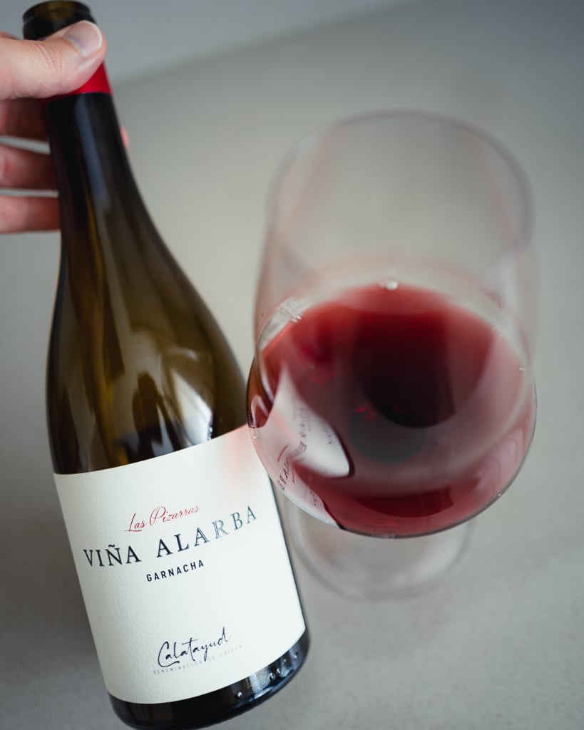 Hand holding the Viña Alarba Garnacha bottle above a glass of red wine