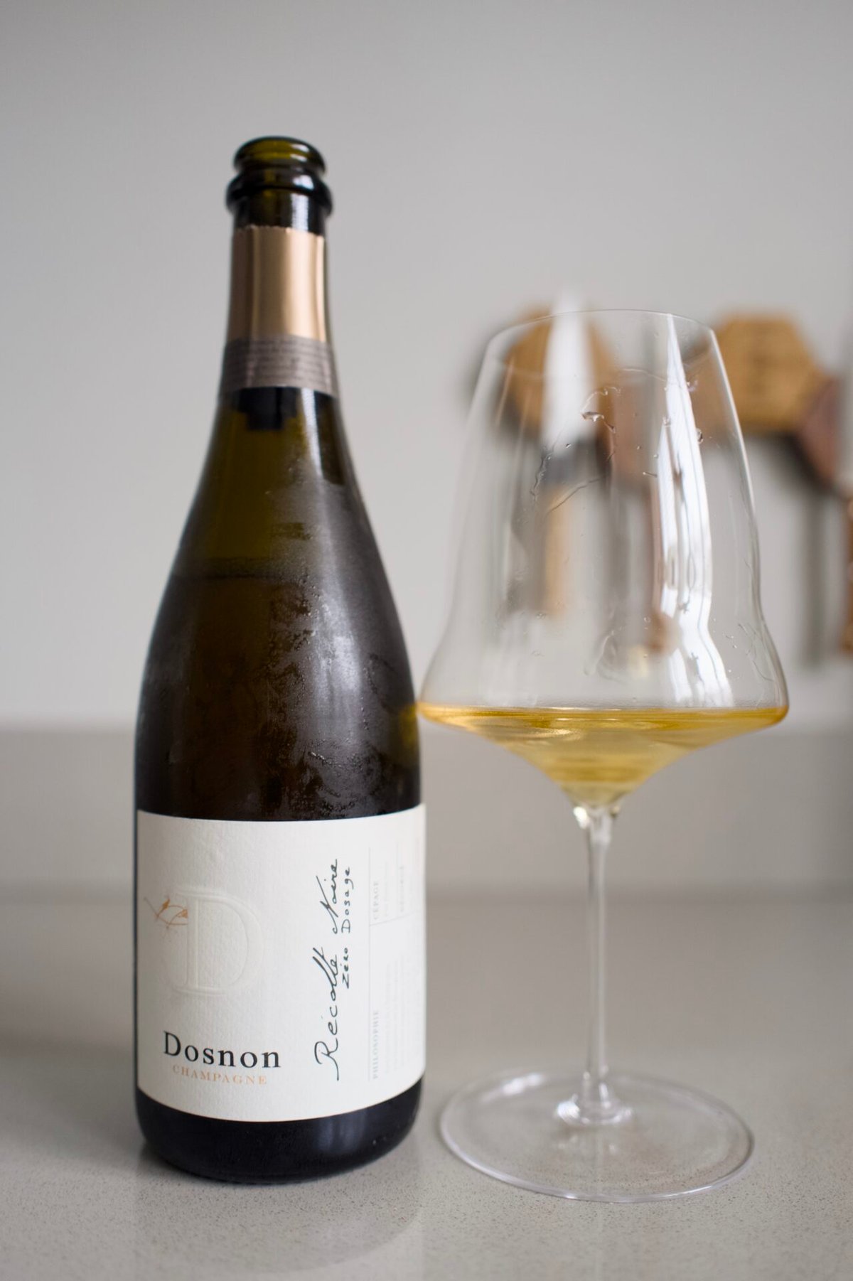 Dosnon champagne bottle next to a glass of golden champagne