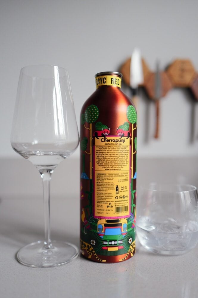 Back of the illustrated Cherrapunji gin tin showing botanicals text, with glass and tumbler