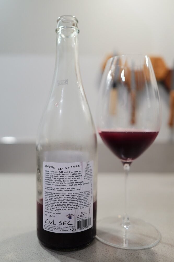 Back of the Cul Sec bottle showing the printed ingredient text beside a glass of dark red drink