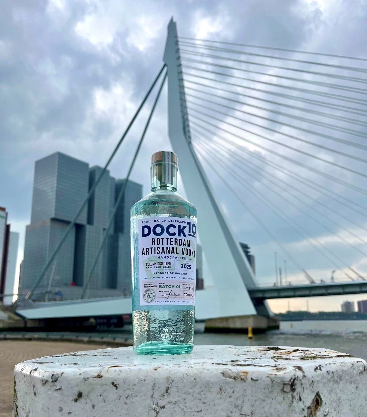 DOCK10 Rotterdam Vodka bottle on a post in front of the white Erasmus Bridge and Rotterdam skyline