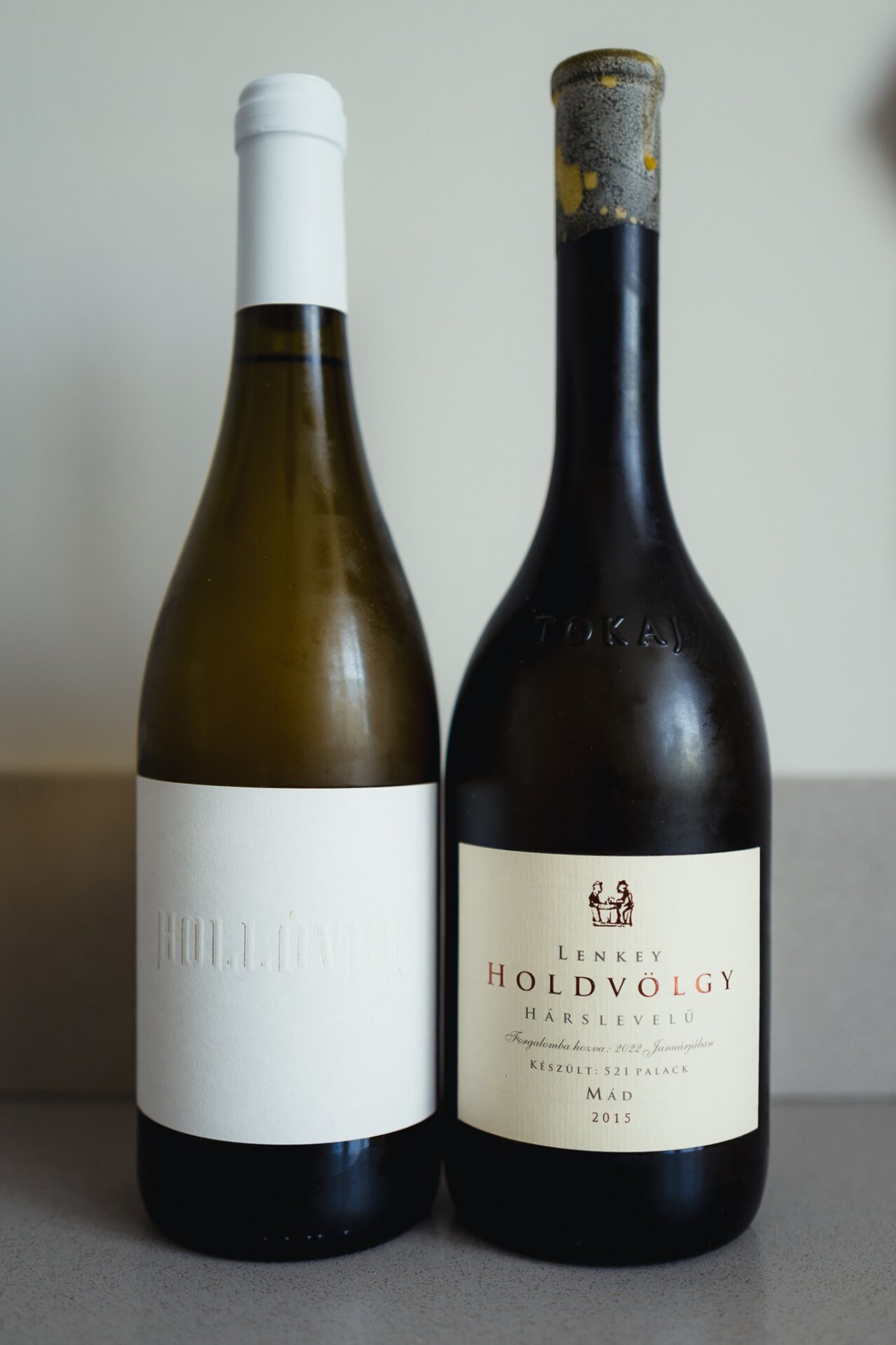 Two dry Tokaji bottles side by side: a pale Hollóvár Furmint and a Lenkey Holdvölgy Hárslevelű
