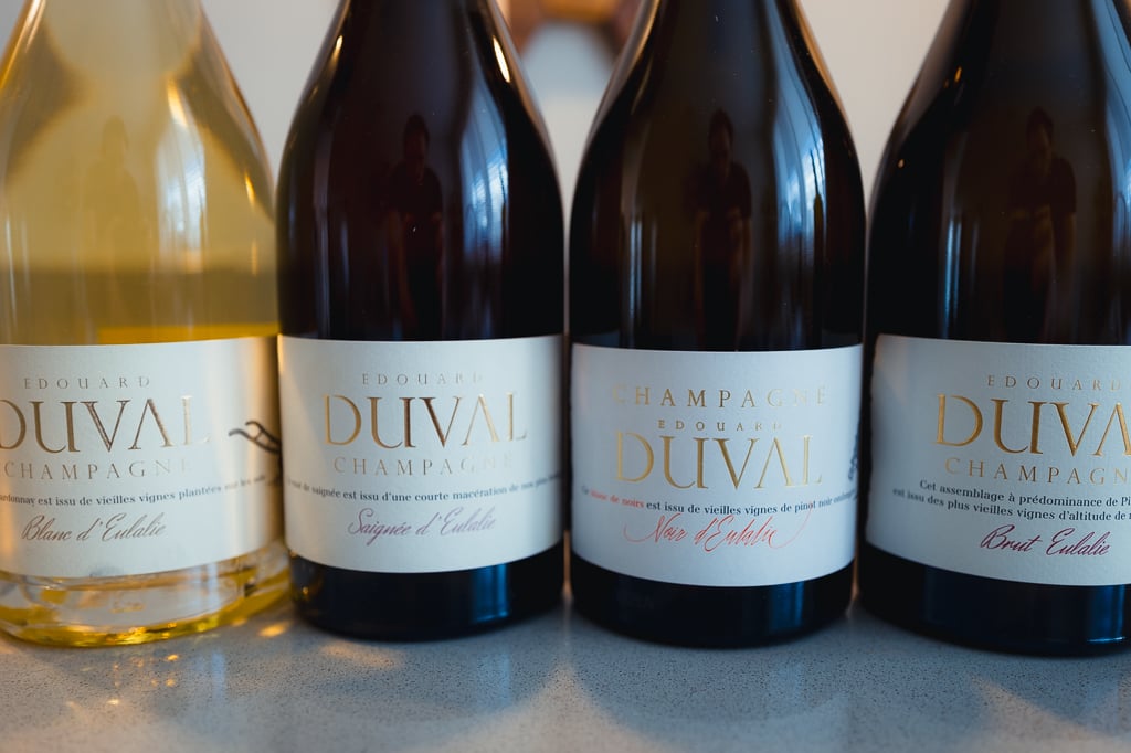 Close-up of four Edouard Duval Champagne bottles in a row showing their cream and gold labels