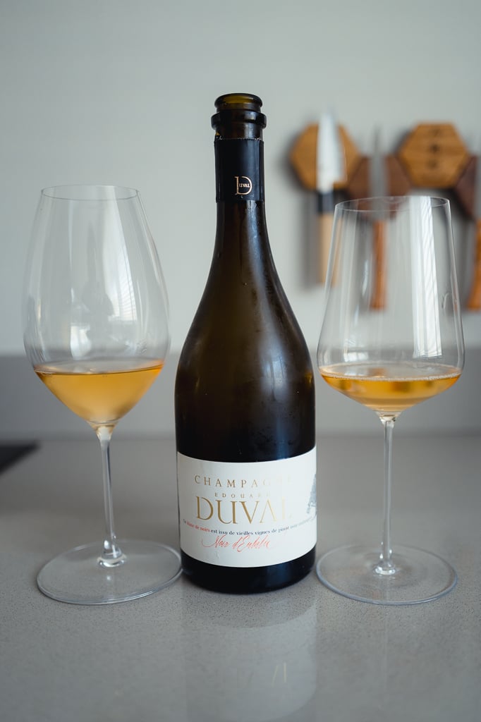 Edouard Duval Noir d'Eulalie bottle flanked by two glasses of amber champagne on a counter