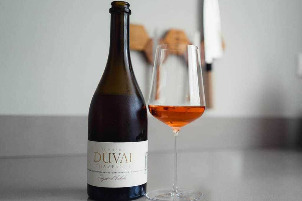 Edouard Duval Saignée d'Eulalie bottle held over a glass of salmon-pink rosé champagne
