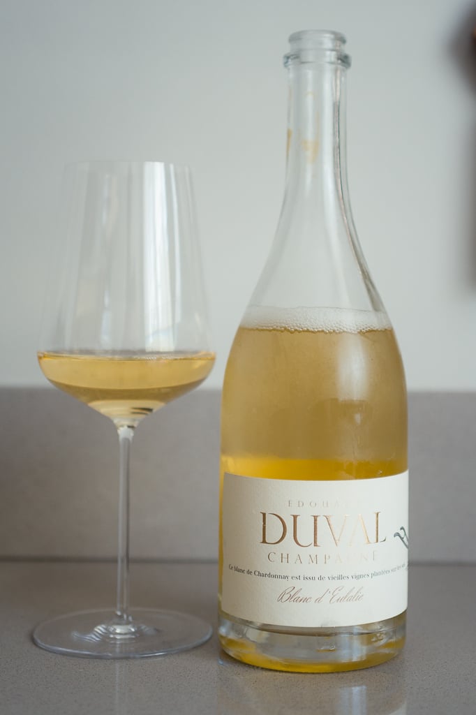 Edouard Duval Blanc d'Eulalie clear bottle beside a glass of pale golden champagne on a counter