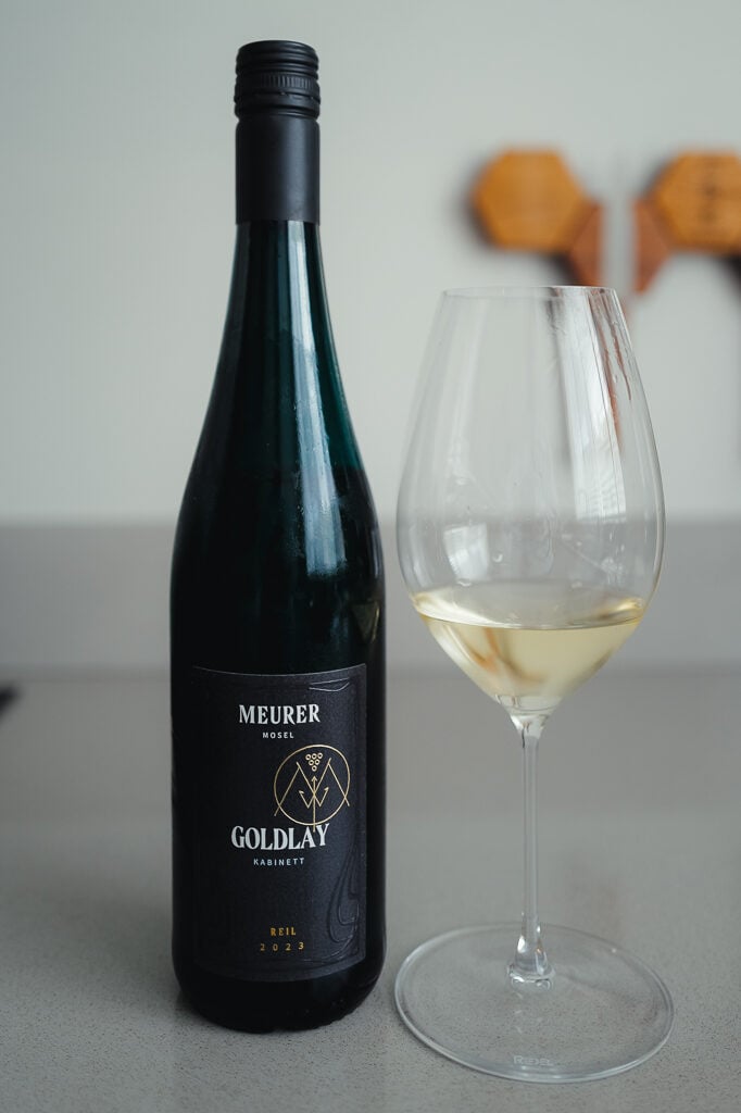 Meurer Goldlay Kabinett green bottle with dark label standing beside a glass of white wine