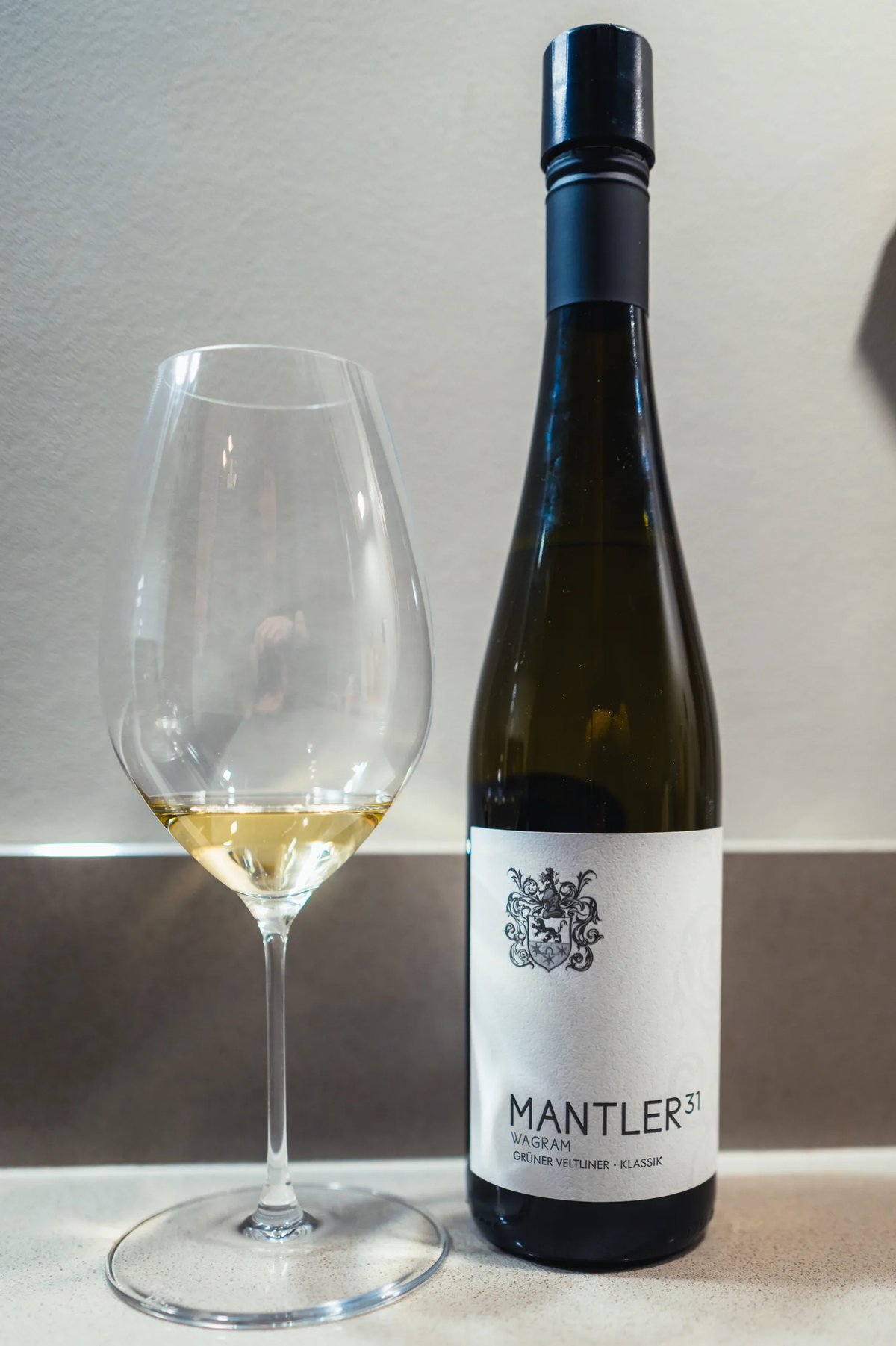 Mantler 31 Grüner Veltliner Klassik bottle beside a glass of pale white wine