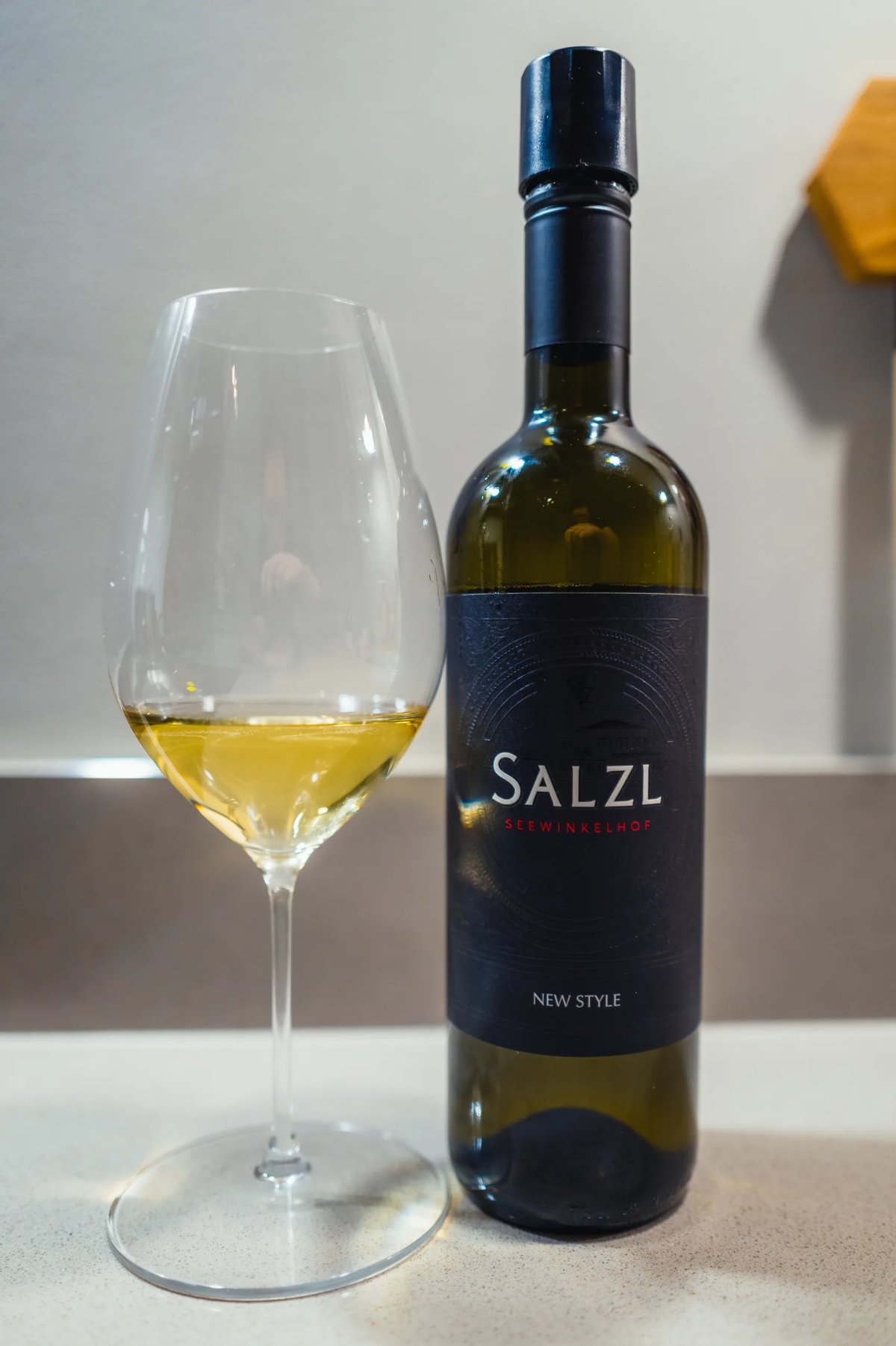 Salzl New Style bottle with a black label beside a glass of white wine
