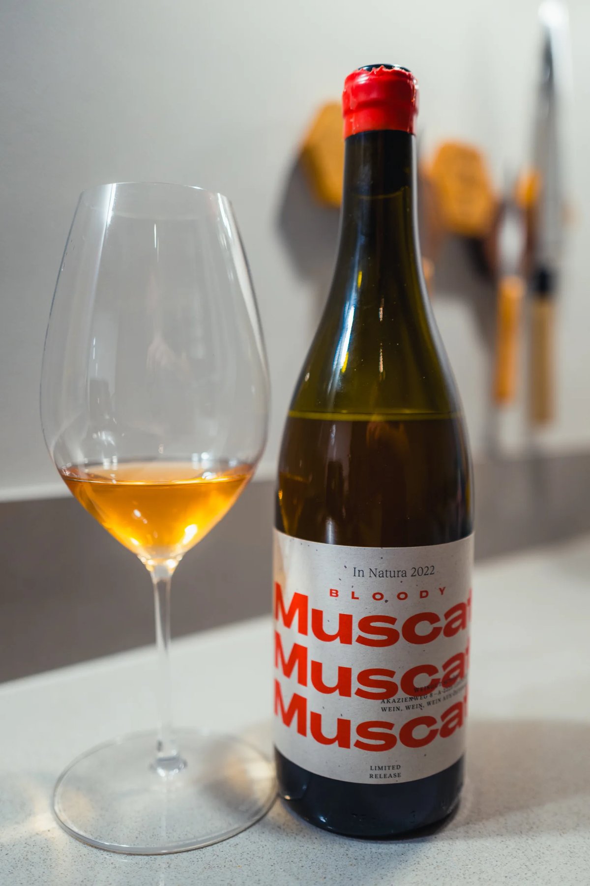 Schödl Bloody Muscat bottle with red cap beside a glass of amber-orange wine