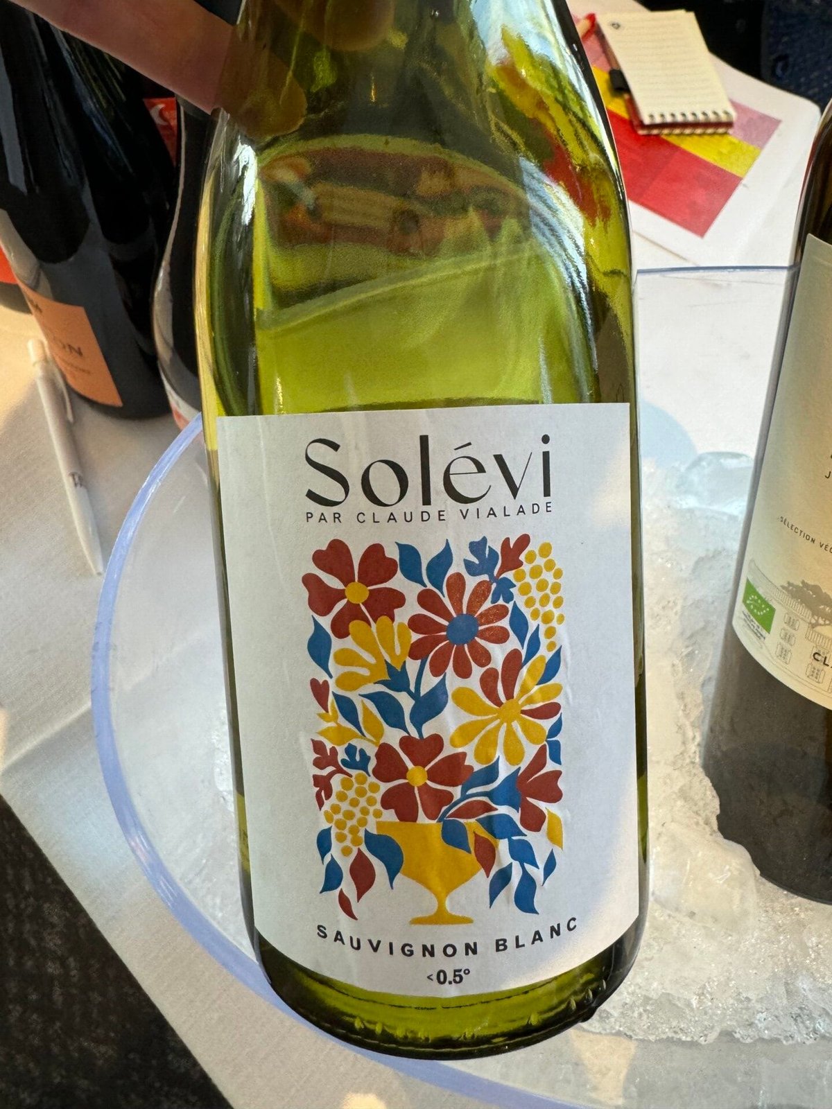 Bottle of Solévi par Claude Vialade Sauvignon Blanc with a colourful floral label on ice