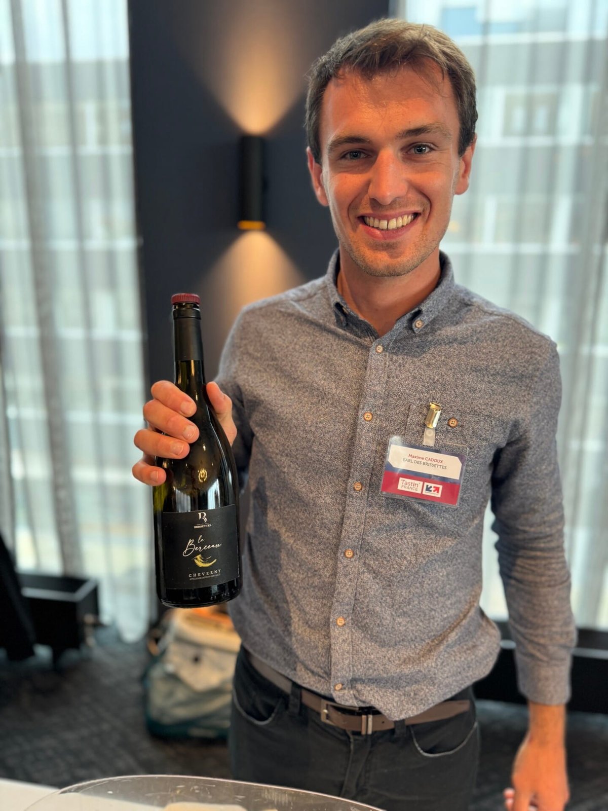 Smiling winemaker holding a bottle of Domaine des Brissettes Le Berceau Cheverny red
