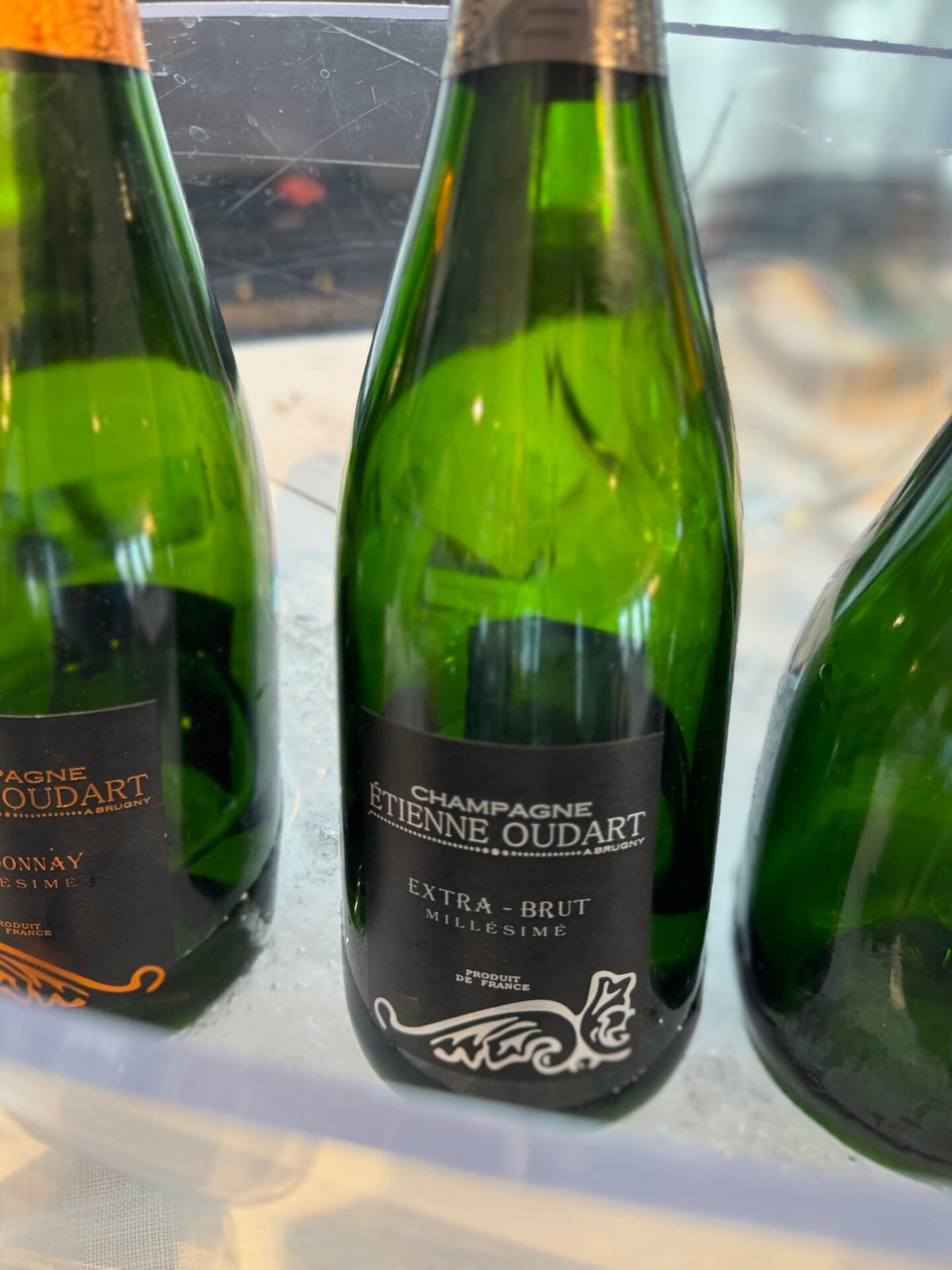 Two green Champagne Étienne Oudart Extra-Brut Millésimé bottles chilling in a tub of ice