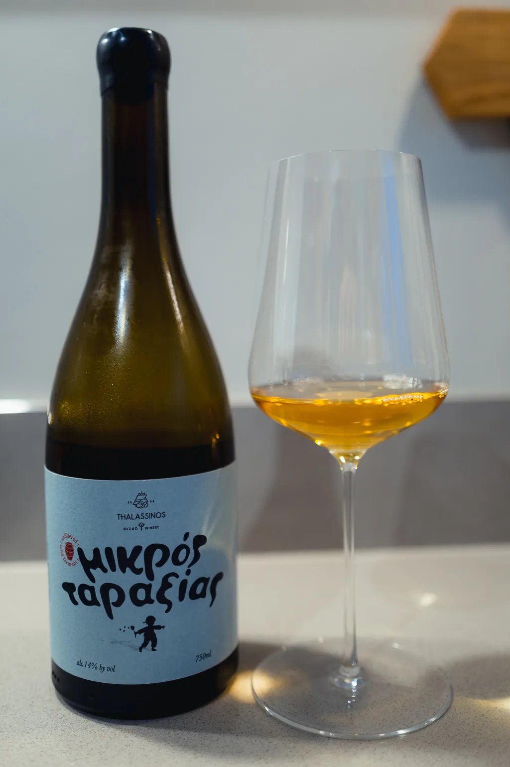 Thalassinos Mikrós Taraxías Vidiano bottle beside a glass of amber natural wine