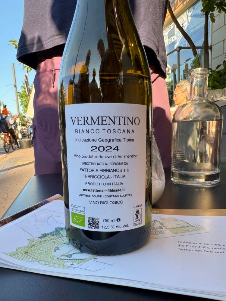 Back label of Fibbiano Vermentino Bianco Toscana 2024 on an outdoor table with a vineyard map