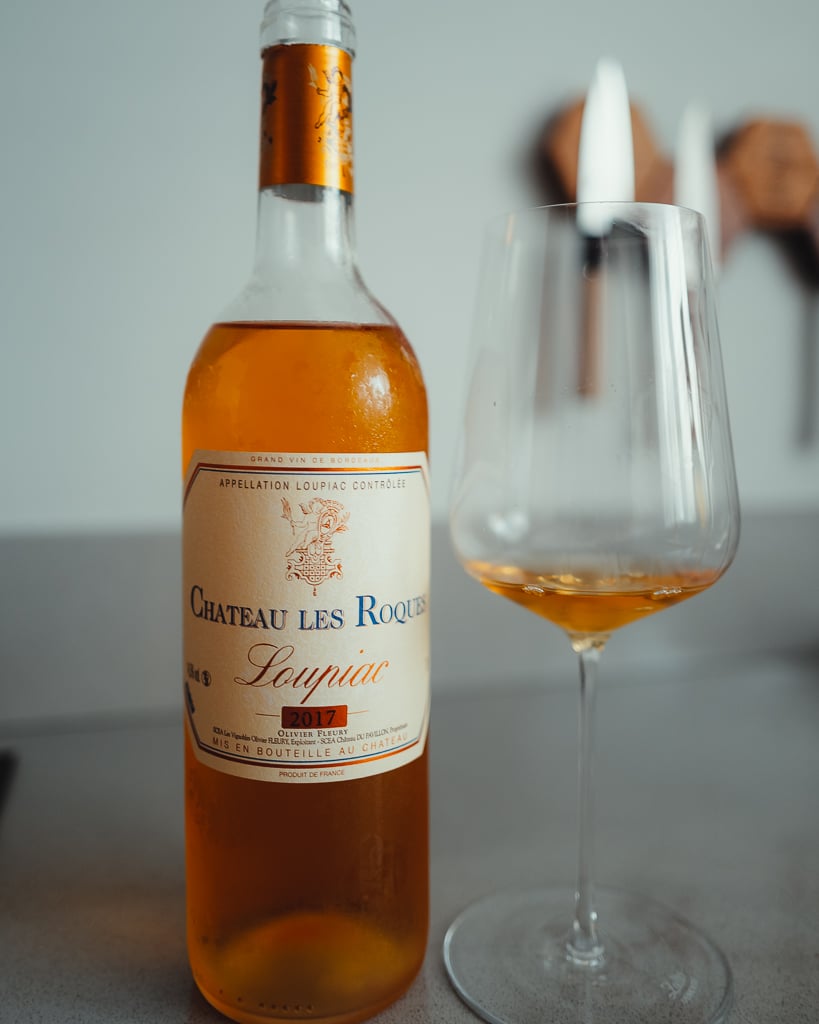 Standing bottle of Graves 2022 Château Fleury red beside a glass of red wine