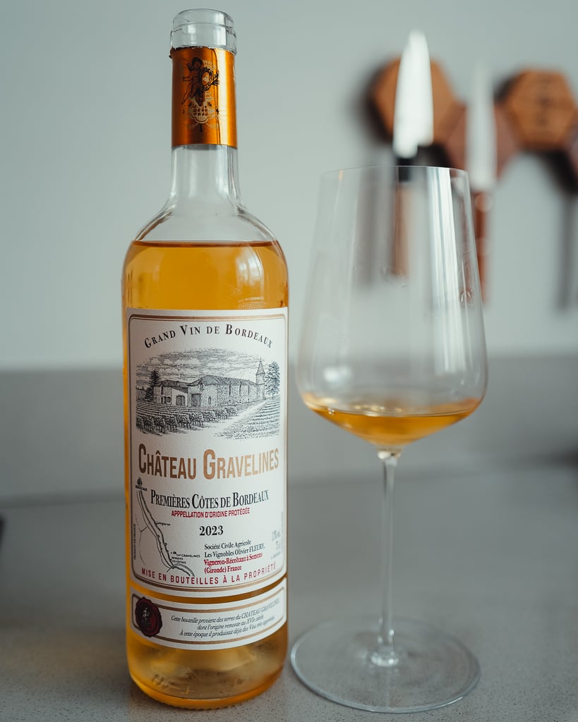 Château Gravelines sweet white bottle with golden wine beside a glass of amber wine