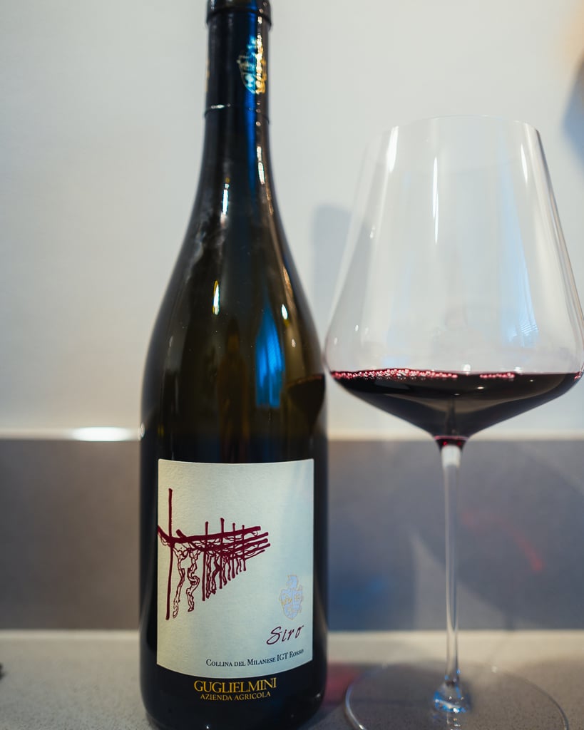 Guglielmini Siro red bottle with a vine-sketch label beside a glass of red wine
