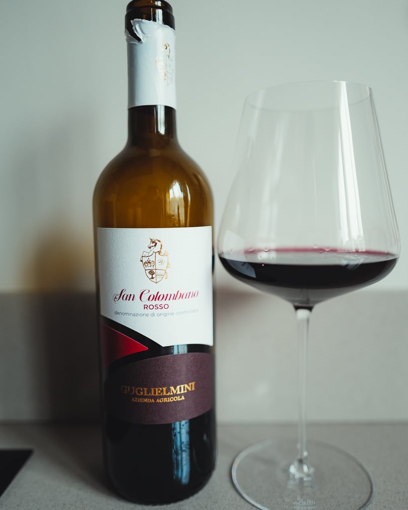 Guglielmini San Colombano Rosso bottle with cream label beside a glass of red wine