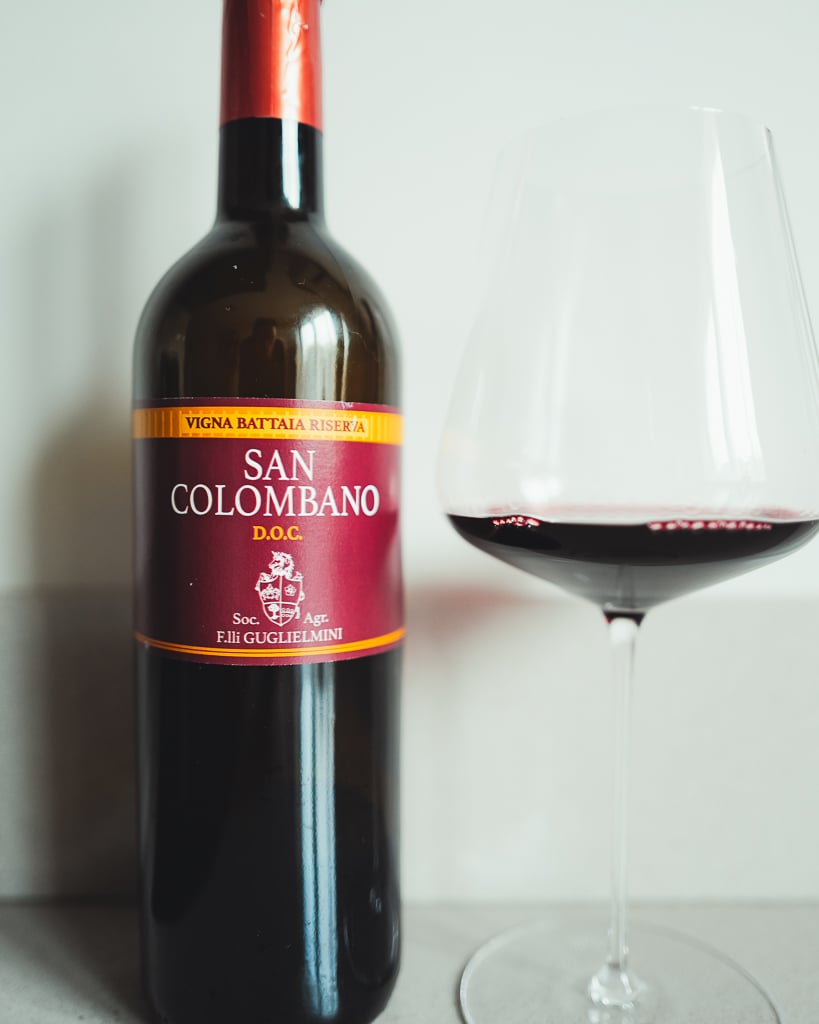 Guglielmini San Colombano Vigna Battaia Riserva red bottle beside a glass of red wine