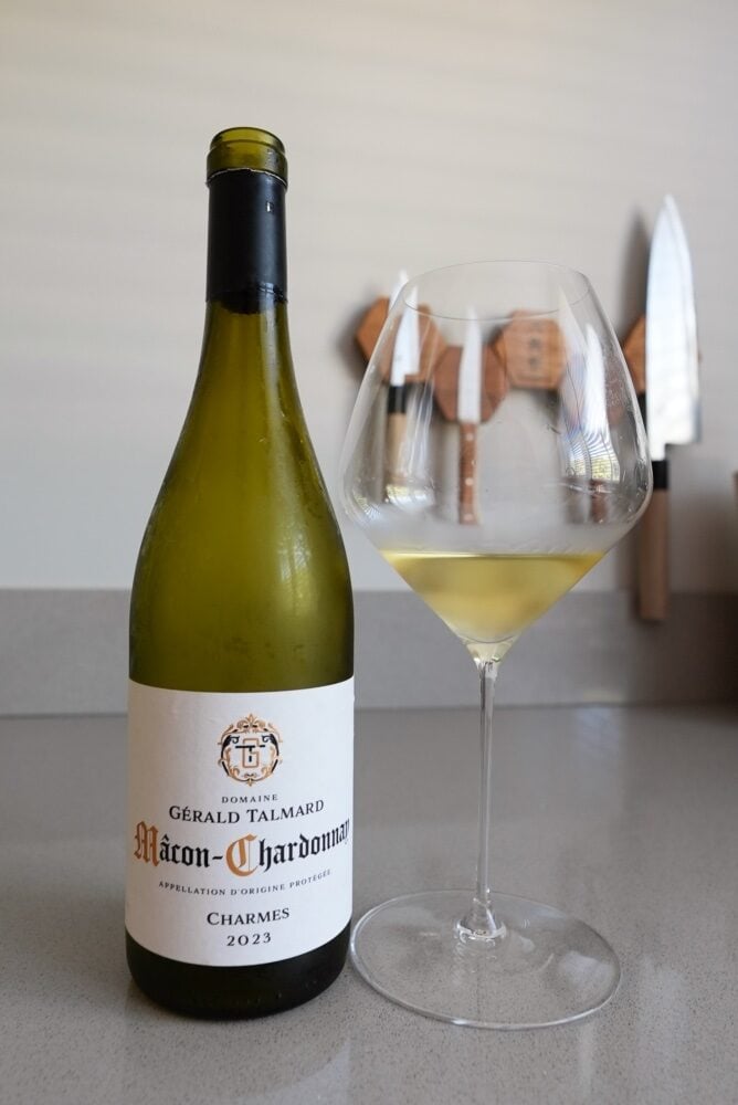 Bottle of Gerald Talmard Macon-Chardonnay Charmes 2023 next to a glass of white wine on a kitchen counter