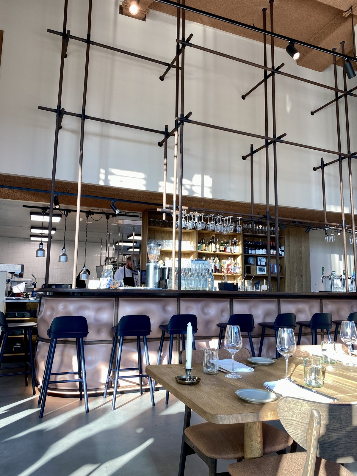 Cafe Jansen bar with copper counter, blue stools and tall industrial metal frames