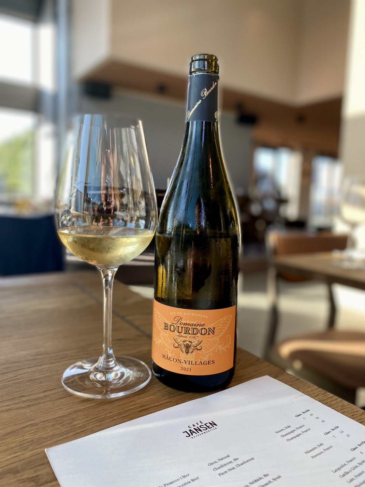 Bottle of Domaine Bourdon Macon-Villages with a glass of white wine and the Cafe Jansen menu