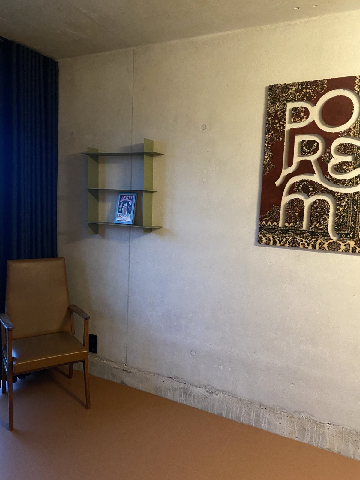 Quiet corner with a vintage leather chair, wall shelf and a textured red and gold artwork