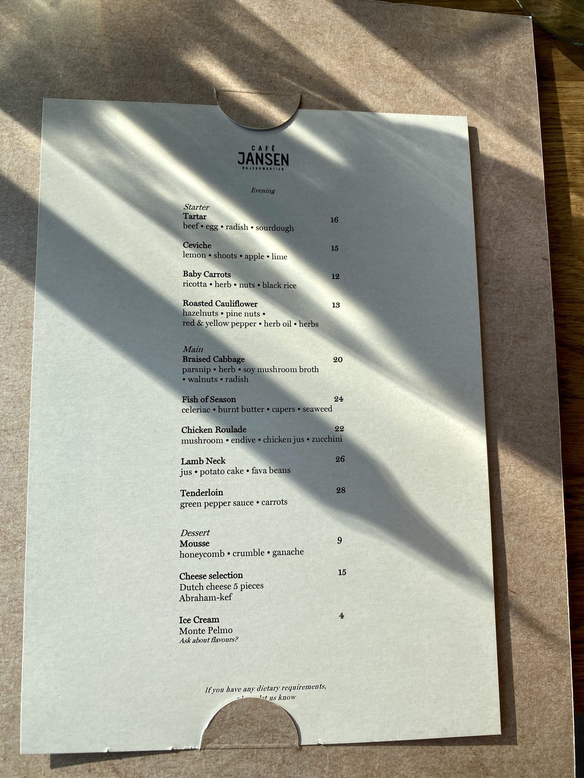 Cafe Jansen evening menu card listing starters, mains and desserts on cream paper