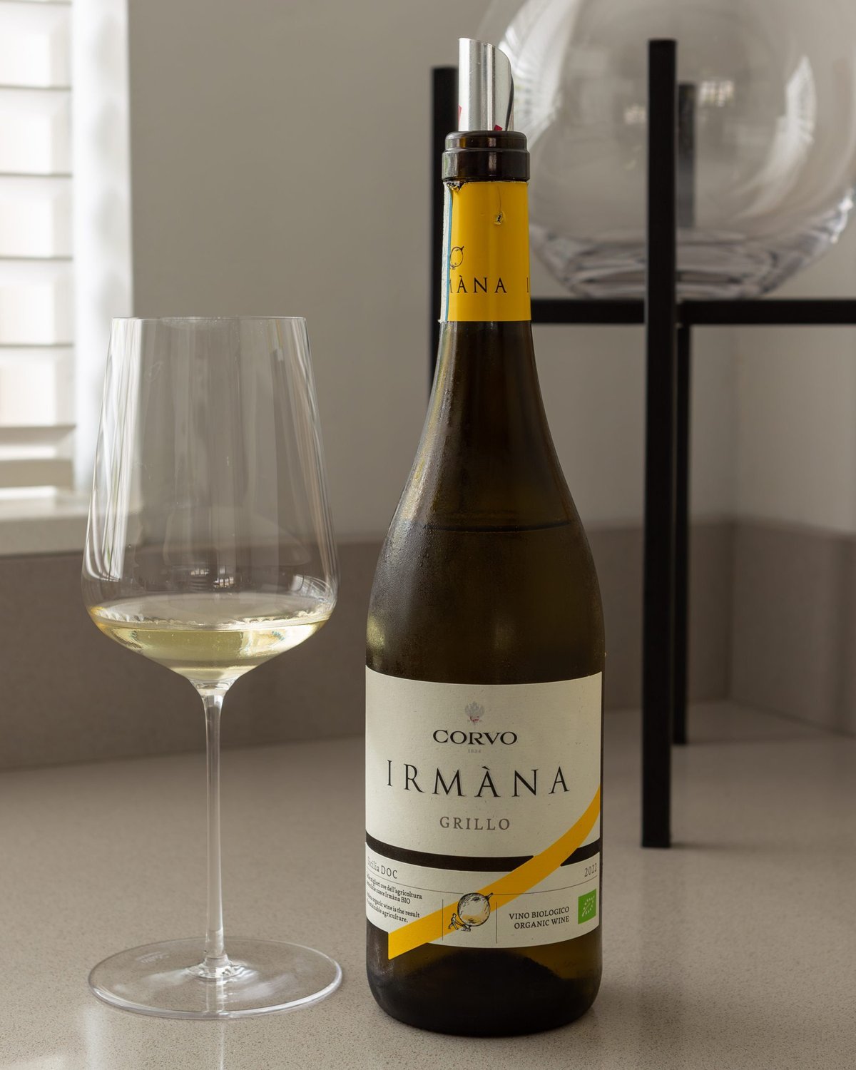 Bottle of Corvo Irmana Grillo organic Sicilian white wine beside a glass of white wine