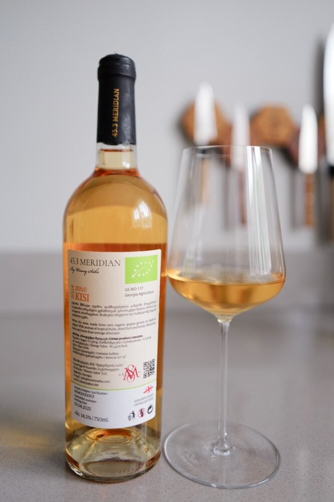 Back label of the 45.3 Meridian Kisi 2024 with EU organic logo beside a glass of golden wine