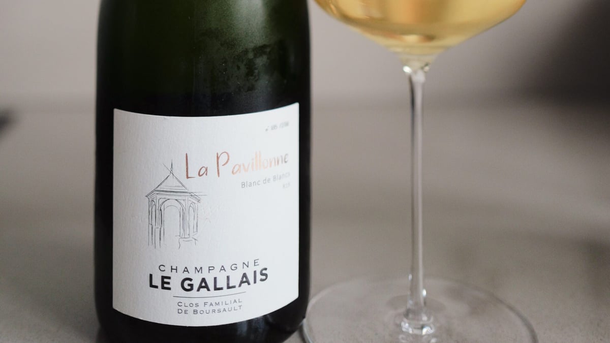 Close-up of the La Pavillonne Le Gallais Blanc de Blancs label beside a glass of golden champagne