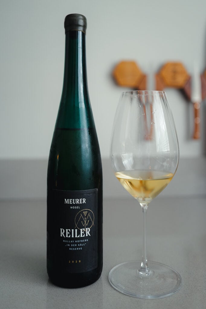 Tall green Meurer Reiler Mullay Hofberg Reserve 2020 bottle next to a glass of white wine