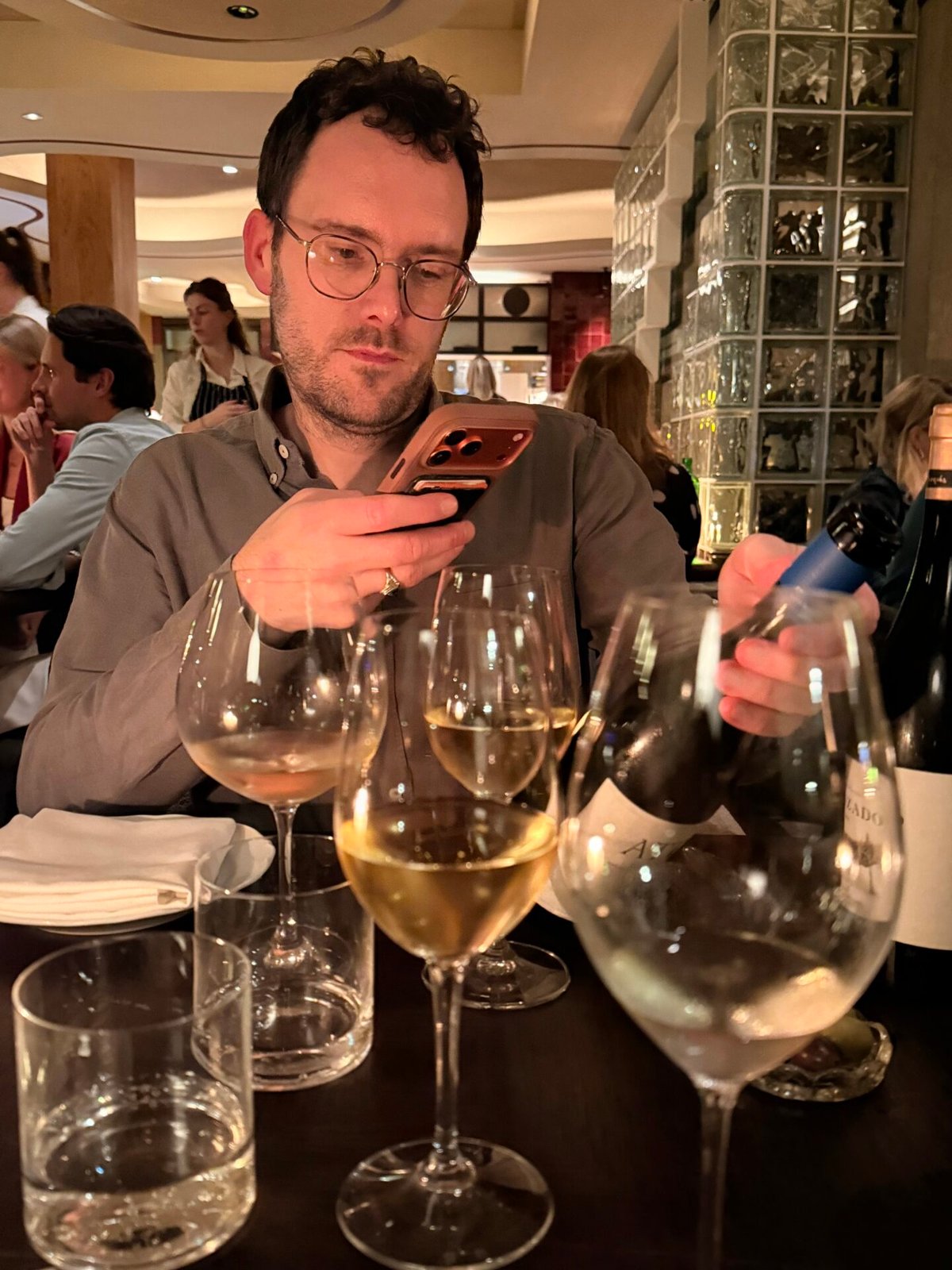 Hand holding a Trenzado white wine bottle from Tenerife beside glasses at a restaurant table