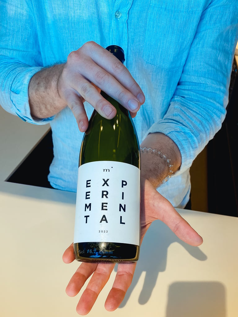 Hand holding a Minimalist Wines Experimental white bottle with its minimalist letter label