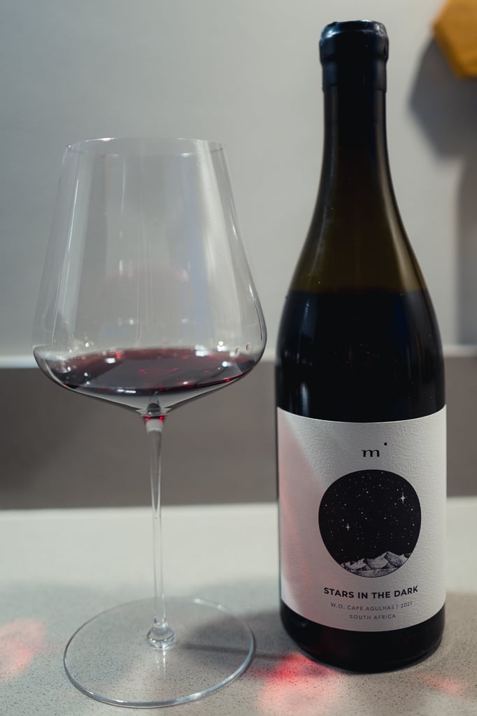Minimalist Wines Stars in the Dark bottle standing beside a glass of red wine