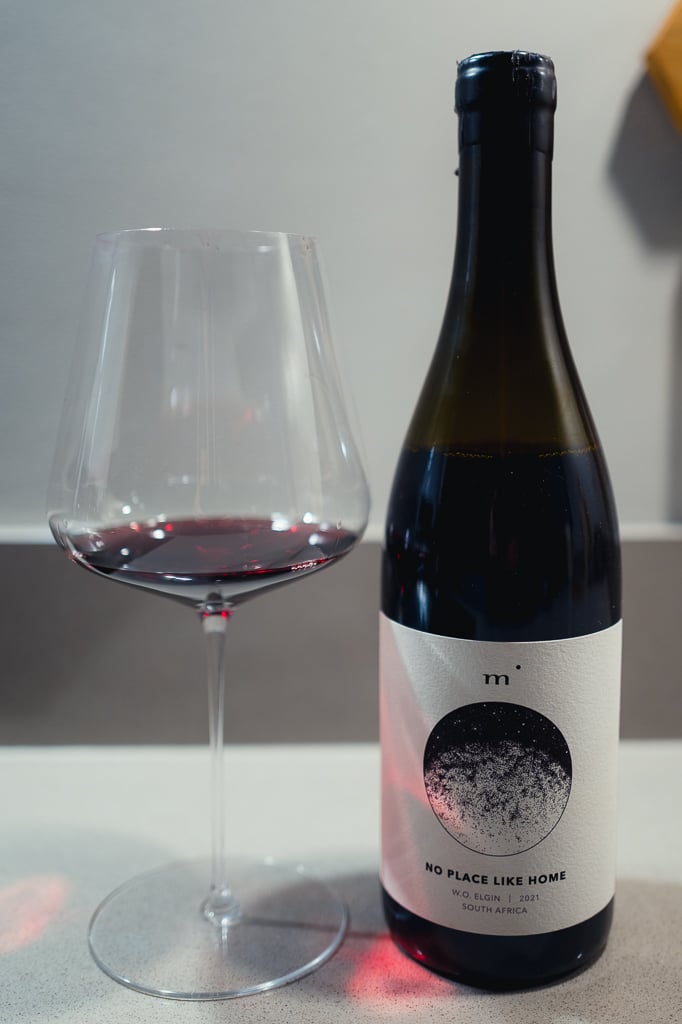 Minimalist Wines No Place Like Home bottle standing beside a glass of red wine
