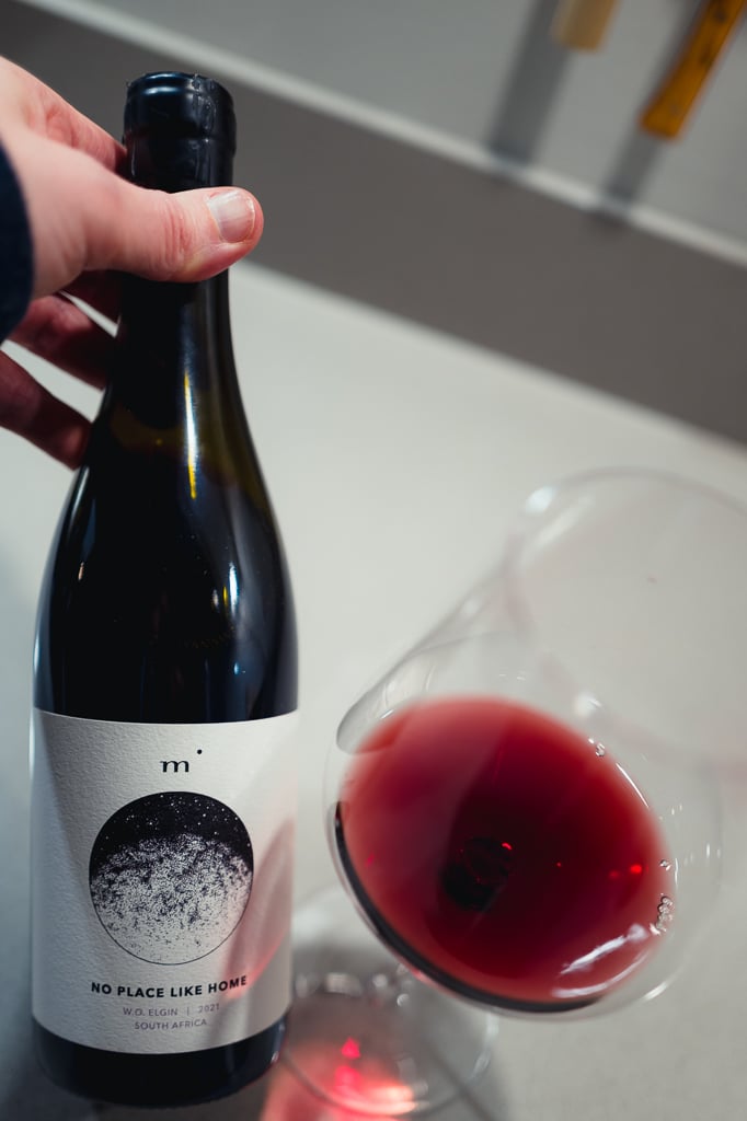 Minimalist Wines No Place Like Home bottle held beside a glass of red wine
