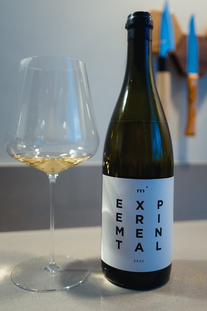 Minimalist Wines Experimental white bottle standing beside a glass of pale white wine