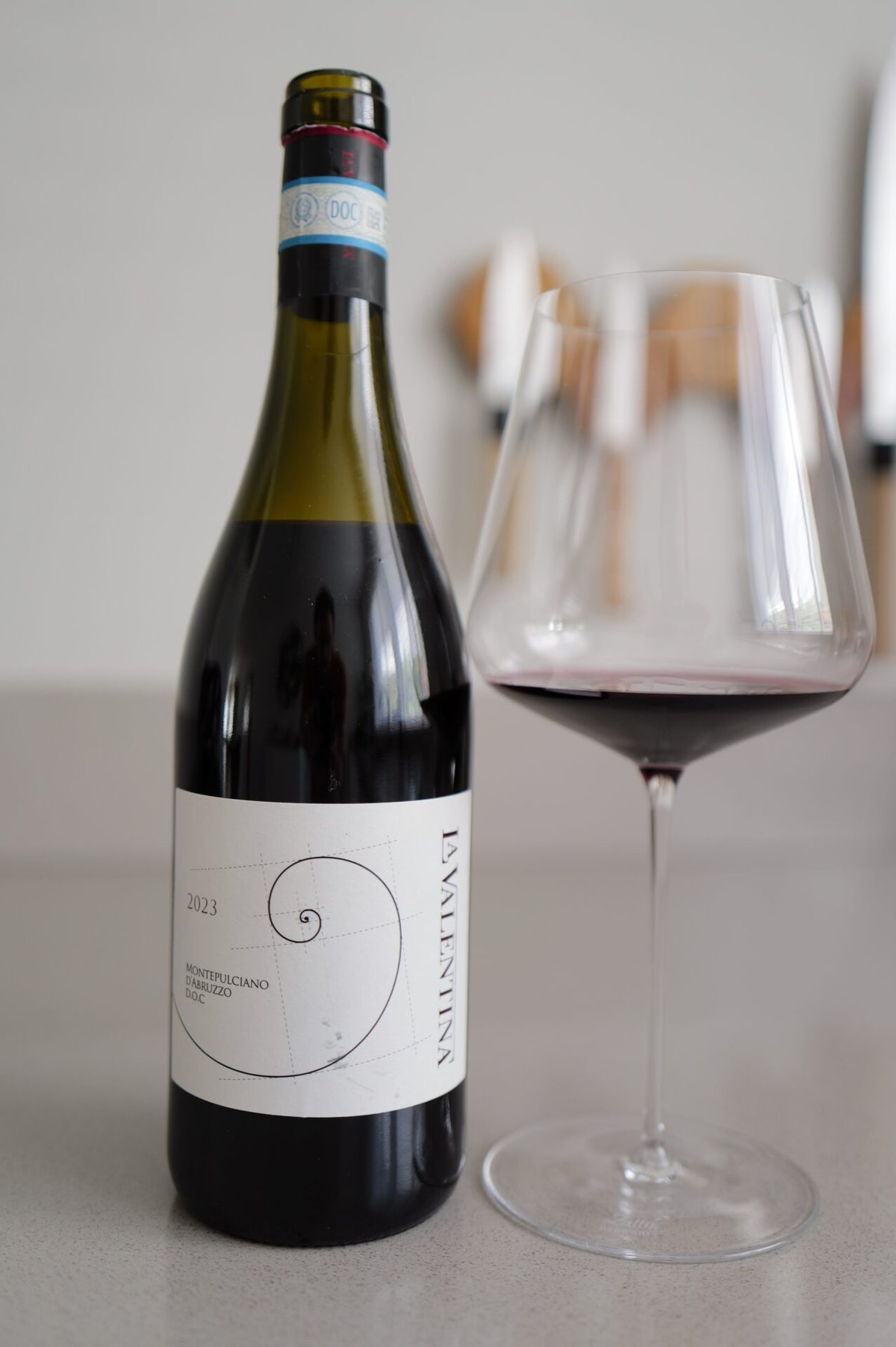 La Valentina Montepulciano d'Abruzzo bottle with spiral label beside a glass of red wine