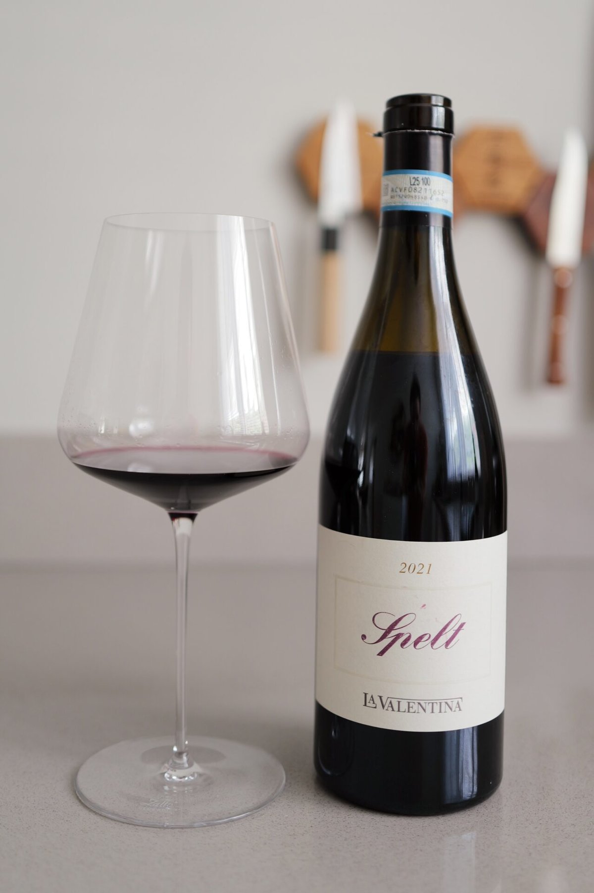 La Valentina Spelt Riserva bottle beside a glass of red wine on a counter