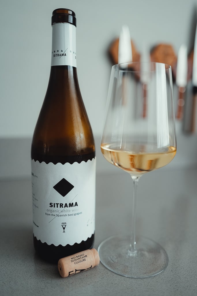 Sitrama organic white wine bottle beside a glass of golden wine and a cork