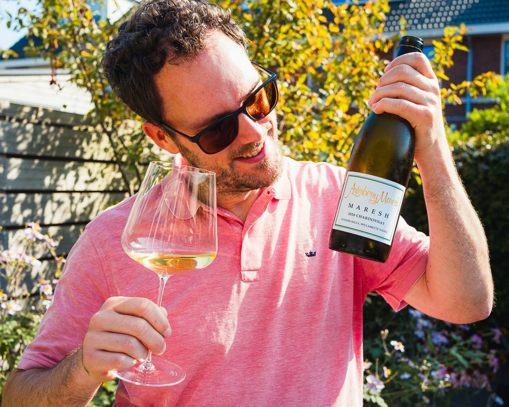 Man in sunglasses outdoors holding an Arterberry Maresh bottle and a glass of white wine