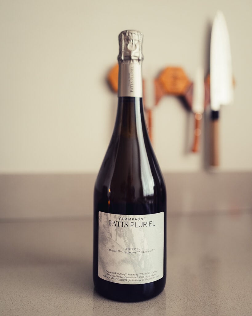 Single Patis Pluriel Les Sèves champagne bottle on a counter with a knife block behind